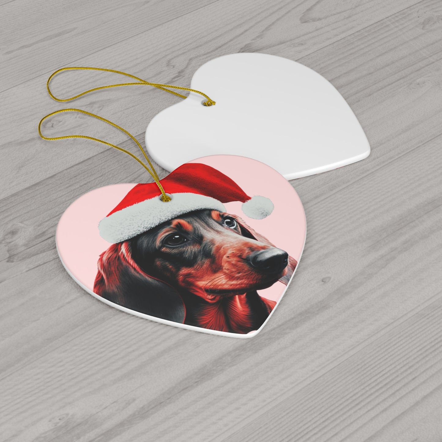 A heart or circle-shaped Christmas ornament featuring a cute Dachshund in a Santa hat on a pastel pink background, adding a charming touch to holiday decor